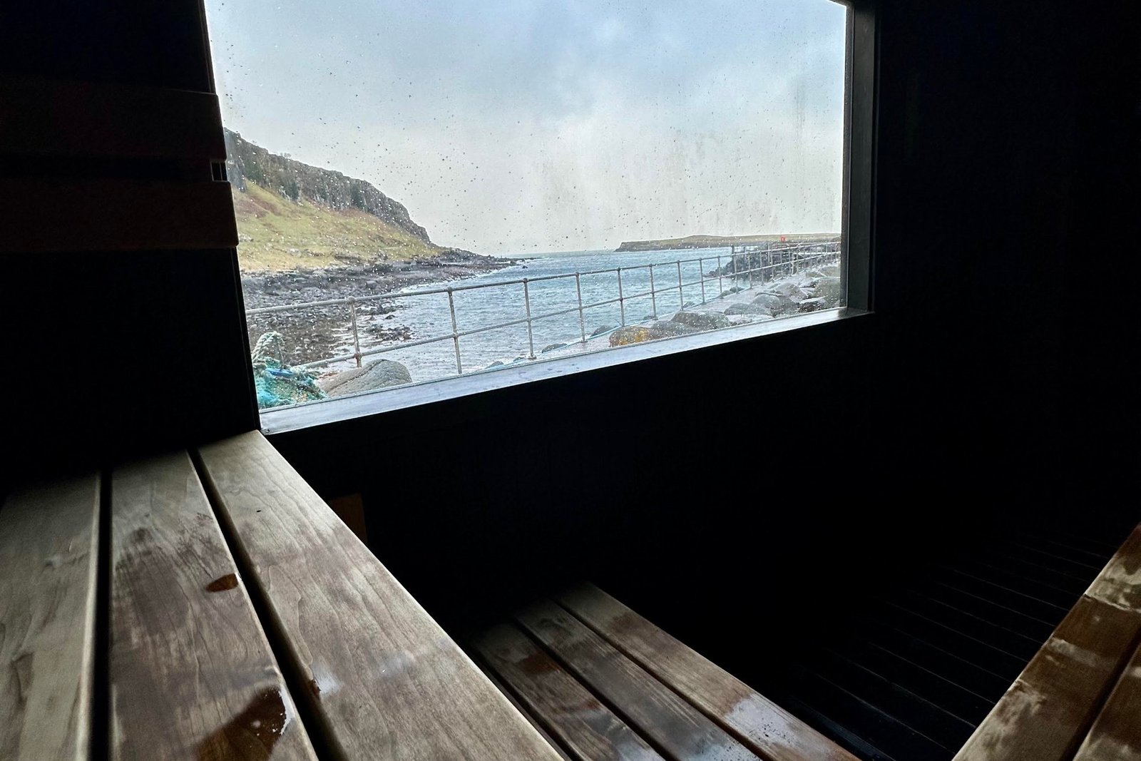 Looking out to sea from inside Staffin Sauna, with wooden benches in the foreground